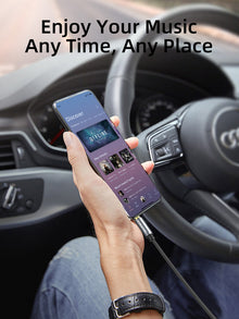 3.5mm AUX extension cable with gold-plated 3.5mm plug held near a car dashboard